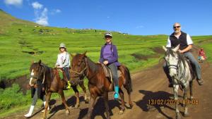 three people riding horses on a dirt road at Libibing chalets in Mokhotlong