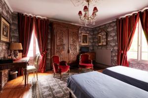 a bedroom with two beds and a desk and red chairs at Manoir des Lions de Tourgéville in Deauville