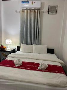 ein Schlafzimmer mit einem Bett mit zwei Handtüchern darauf in der Unterkunft Jasmine Place House in Luang Prabang