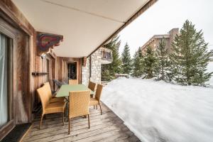 a deck with a table and chairs in the snow at Les Balcons de Pralong Courchevel 1850 - by EMERALD STAY in Courchevel