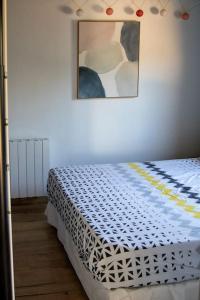 uma cama num quarto com uma fotografia na parede em La maisonnette de Joséphine em Saint-Jean-des-Mauvrets