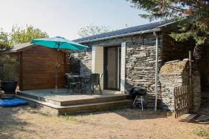 a patio with an umbrella and a table and chairs at La maisonnette de Joséphine in Saint-Jean-des-Mauvrets