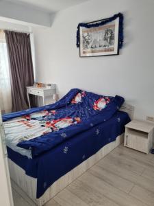 a bedroom with a bed with a blue comforter at Sweet Home in Iaşi