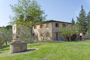 une grande maison en pierre avec un arbre dans la cour dans l'établissement Agriturismo Canale, à Peccioli