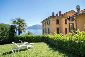 アルジェーニョにあるVilla Peroni Lake Como Classic with Swimming poolの家の隣の芝生に座る白い椅子2脚