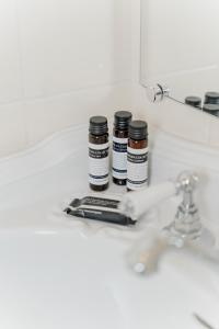 Tres botellas de medicina sentadas en el lavabo del baño. en Landgoed Halsaf, en Babberich