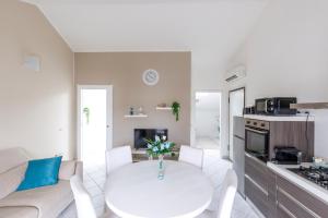 a white living room with a white table and a kitchen at Elly's Home [Parcheggio Privato] in Ravenna