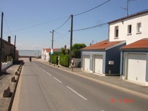 an empty street with houses and a person on a motorcycle at L' Ecume de Mer in Châtelaillon-Plage