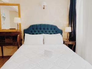 a bedroom with a bed with a blue headboard and a mirror at Five Seasons Pension in Nafplio