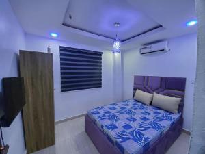 a bedroom with a purple bed and a window at DINERO DIAMOND - ONE BED APARTMENT in Lagos