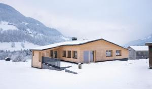 a house in the snow with mountains in the background at Ferienhaus Schihütte Mellau in Mellau