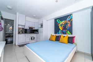 una camera da letto con un letto e un dipinto di un cane di 1013 studio Garden City a Playa Fañabe