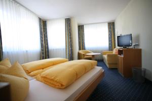 um quarto de hotel com uma cama amarela e uma televisão em Hotel Linde Pfalz em Silz