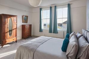 a bedroom with a bed and a dresser and windows at Beautiful Sea View Apartment in St Leonards on Sea in St. Leonards