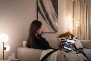 a woman sitting on a couch with a tablet at The Wilton Suite - Your Private 5* Escape! in Glasgow