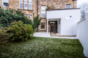 een tuin met een wit gebouw en een deur bij The Wilton Suite - Your Private 5* Escape! in Glasgow