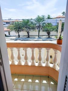 uma varanda com vista para a praia e palmeiras em Maré Hostel Itapuã em Salvador