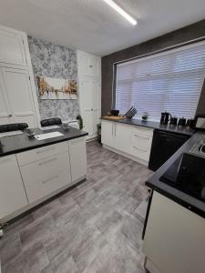 a kitchen with white cabinets and a large window at The View Sandbach in Sandbach
