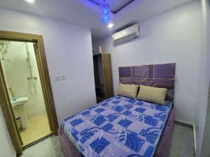 a bedroom with a bed with a blue comforter at DINERO JADE - One Bedroom Apartment in Lagos