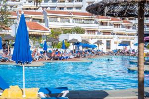 una piscina con ombrelloni e persone in un resort di 1013 studio Garden City a Playa Fañabe