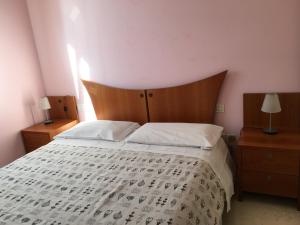 a bedroom with a large bed with white sheets and a wooden headboard at Aparthotel Manfrè in Vedelago