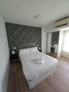 a bedroom with a white bed with a floral wall at II Precioso apartamento con vistas a la Catedral in Salamanca