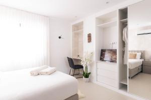 a white bedroom with a bed and a desk at Penthouse with jacuzzi and sea view, Morabeza Deluxe in Mindelo