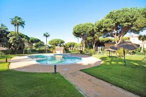 a swimming pool with an umbrella in a park at Chalet Cormoran in Chiclana de la Frontera