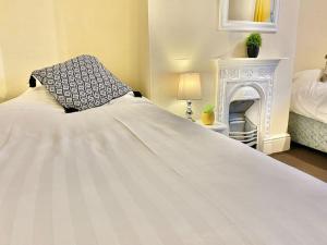 a bedroom with a large white bed and a fireplace at EasyRest House 2 Grantham - 6 Beds & Free Parking - Easy Location - Access to A1, Town Centre & Shops in Grantham