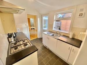 uma cozinha com um fogão e um lavatório em EasyRest House 2 Grantham - 6 Beds & Free Parking - Easy Location - Access to A1, Town Centre & Shops em Grantham