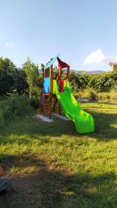 um parque infantil com um escorrega verde na relva em Agriturismo Gusto Nocciola em Bagnoli