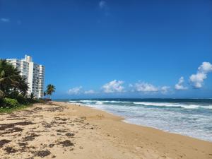 - une plage avec un bâtiment et l'océan dans l'établissement Enjoy our Luxurious Penthouse in Condado!, à San Juan