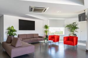 ein Wohnzimmer mit einem Sofa und roten Stühlen in der Unterkunft Aparthotel Grel Suite 208 in Chiaramonte Gulfi