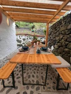 una mesa de madera sentada bajo un techo de madera en Casa Tosca en Fajã de São João