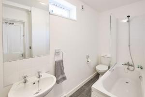 baño blanco con lavabo, bañera y aseo en Beautiful Sea View Apartment in St Leonards on Sea en St. Leonards