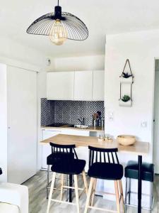 kuchnia ze stołem, krzesłami i lampką w obiekcie Cabourg T2 tout neuf Accès direct mer Grand balcon w mieście Cabourg