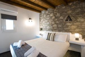1 dormitorio con cama y pared de piedra en Mykonos Amazing Apartments 2, en Mykonos ciudad