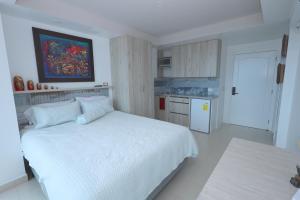a white bedroom with a white bed and a kitchen at Mejor que un Hotel in Salinas