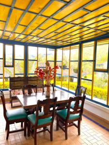 ein Esszimmer mit einem Tisch, Stühlen und Fenstern in der Unterkunft El Rancho de Salento in Salento