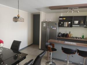 a kitchen with a refrigerator and a table and chairs at Departamento por día 3 dormitorios y 2 baños in Arica