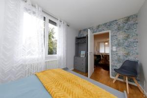 a bedroom with a bed and a chair and a window at Maison « De Ville en Vigne » in Chenôve