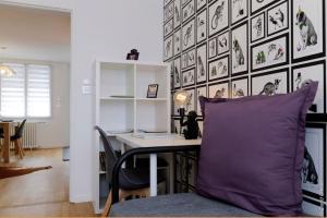 um quarto com uma secretária com uma almofada roxa e uma parede com fotografias em Maison « De Ville en Vigne » em Chenôve