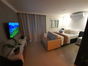 a bedroom with a bed and a couch and a tv at Studio 1202 Guarulhos Aeroporto in Guarulhos