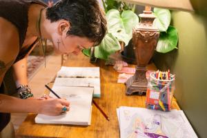 uma mulher está desenhando em um papel sobre uma mesa em CoHo: Conway Hostel em Conway