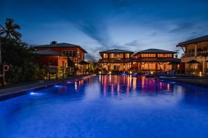 a large swimming pool in front of buildings at night at Ponta de Inhambupe Hotel Boutique & Spa by Slaviero Hoteis in Baixio