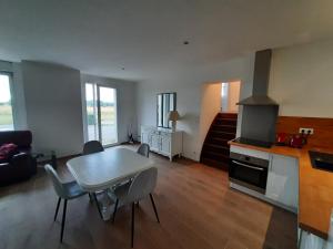 ein Wohnzimmer mit einem Tisch und einer Küche in der Unterkunft LA CLEF DES CHAMPS GITE PERRINE in Brouckerque