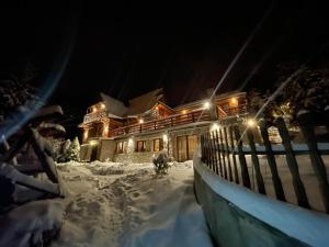 Pienińska Willa Aleksandrówka في شتافنيتسه: منزل مغطى بالثلج في الليل مع أضواء