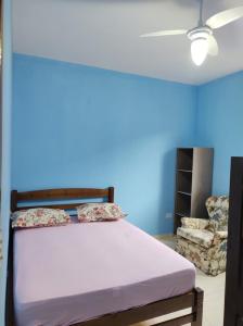 een bed in een kamer met een blauwe muur bij Casa na praia - Balneário Gaivotas in Itanhaém