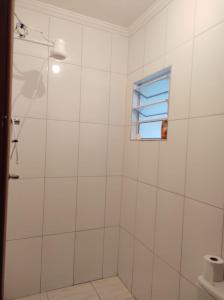 een witte badkamer met een douche en een raam bij Casa na praia - Balneário Gaivotas in Itanhaém