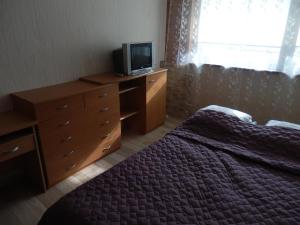 a bedroom with a bed and a dresser with a tv at Linai in Nida +13 photos